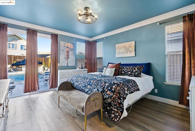 bedroom with wood-type flooring, access to outside, and an inviting chandelier