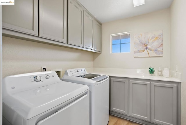 laundry room with cabinets, washer and clothes dryer, and light wood-type flooring