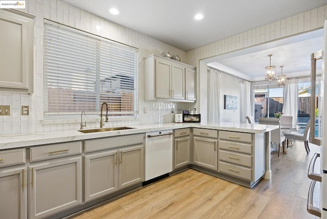 kitchen with kitchen peninsula, sink, light hardwood / wood-style flooring, hanging light fixtures, and gray cabinetry