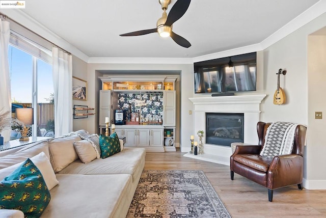 living room with ceiling fan, light wood-type flooring, and crown molding