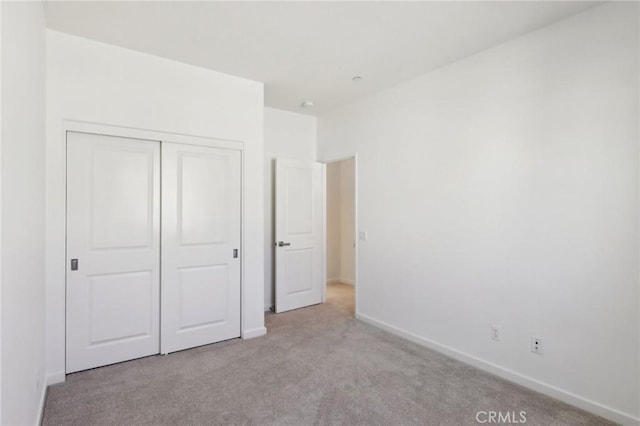 unfurnished bedroom featuring light carpet and a closet