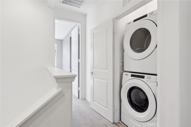 laundry area with light colored carpet and stacked washer and clothes dryer