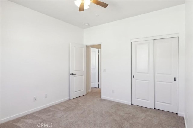 unfurnished bedroom featuring light carpet, ceiling fan, and a closet