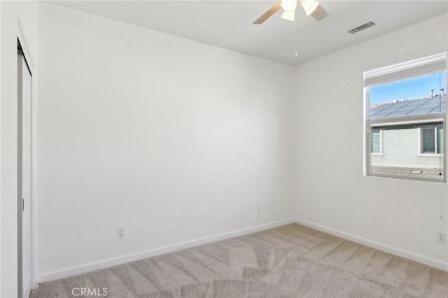 empty room featuring ceiling fan and light carpet