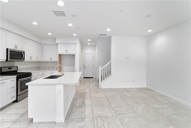 kitchen featuring appliances with stainless steel finishes, sink, a center island with sink, and white cabinets