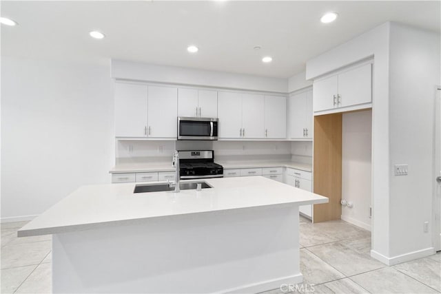 kitchen featuring a kitchen island with sink, sink, white cabinets, and appliances with stainless steel finishes