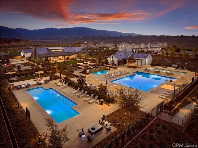 pool at dusk with a mountain view and a patio area