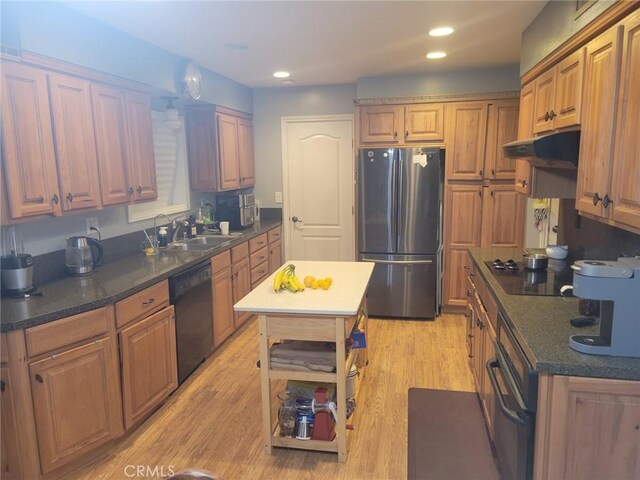 kitchen featuring black appliances, a center island, sink, and light hardwood / wood-style flooring