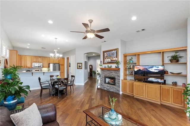 living room featuring dark wood-type flooring, a fireplace, and ceiling fan with notable chandelier