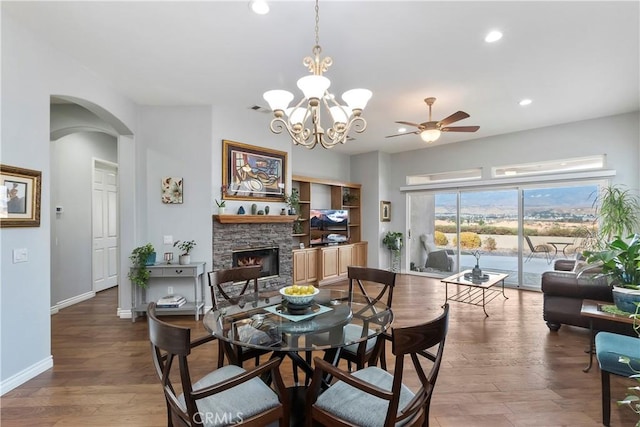 dining area featuring wood-type flooring, ceiling fan, and a fireplace