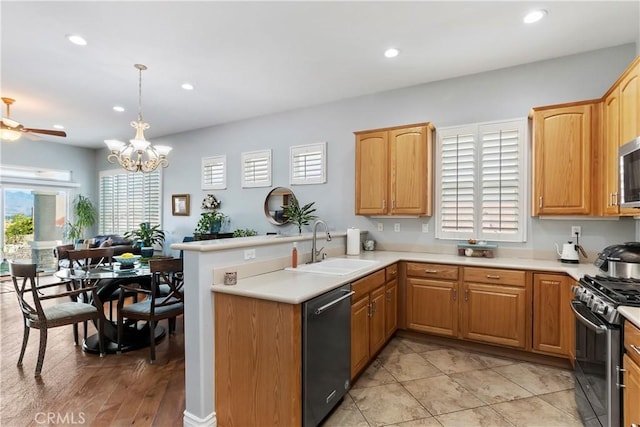 kitchen with sink, hanging light fixtures, kitchen peninsula, stainless steel appliances, and ceiling fan with notable chandelier