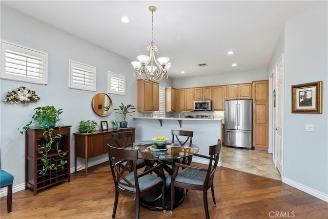 dining space with a notable chandelier and light hardwood / wood-style floors