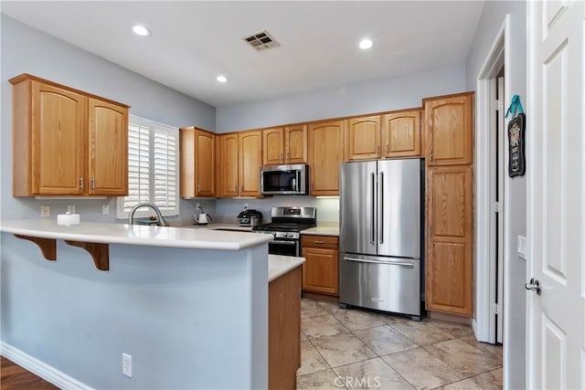 kitchen with sink, a breakfast bar, kitchen peninsula, and appliances with stainless steel finishes