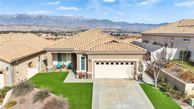 mediterranean / spanish house with a patio, a garage, a mountain view, and a front yard