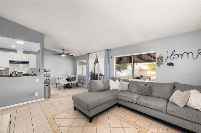 living room with vaulted ceiling, ceiling fan, light tile patterned floors, and a textured ceiling