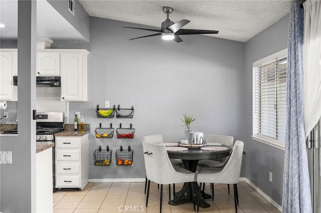 dining area featuring a textured ceiling, ceiling fan, light tile patterned flooring, and lofted ceiling