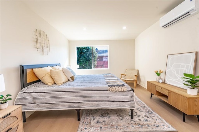 bedroom featuring an AC wall unit and light hardwood / wood-style floors