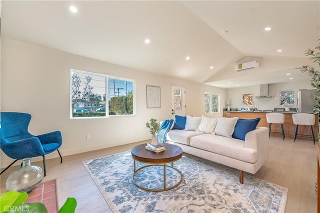 living room with light hardwood / wood-style floors, lofted ceiling, plenty of natural light, and an AC wall unit