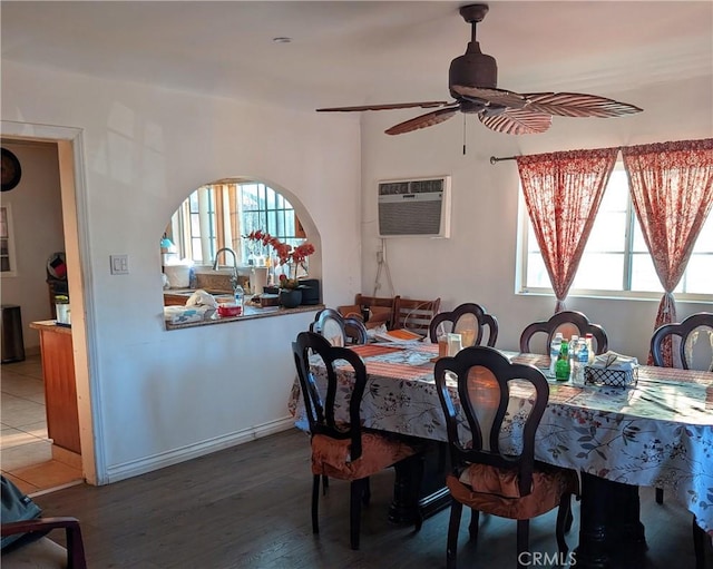 dining area with ceiling fan, sink, hardwood / wood-style floors, and a wall unit AC