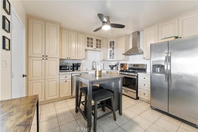 kitchen featuring ceiling fan, light tile patterned floors, appliances with stainless steel finishes, and wall chimney range hood