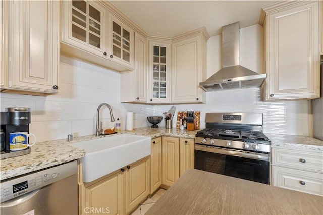 kitchen featuring stainless steel appliances, wall chimney exhaust hood, tasteful backsplash, and sink