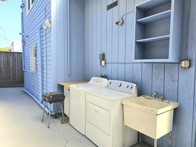 clothes washing area featuring sink, wooden walls, washing machine and clothes dryer, and built in features