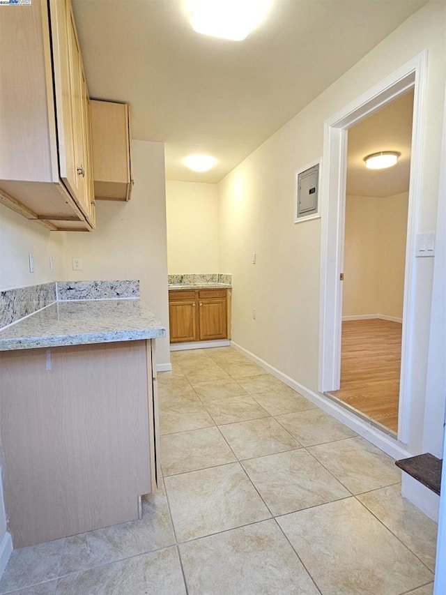 kitchen with light brown cabinetry, light tile patterned floors, and light stone countertops