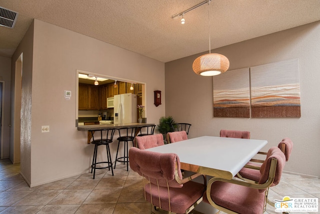 tiled dining area with a textured ceiling and rail lighting