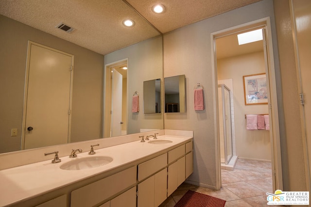 bathroom featuring a textured ceiling, vanity, tile patterned floors, and walk in shower