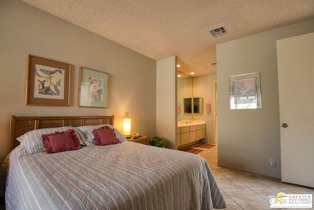 bedroom featuring a textured ceiling, ensuite bathroom, and light tile patterned flooring