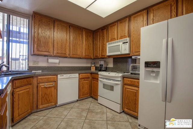 kitchen with light tile patterned flooring, white appliances, and sink