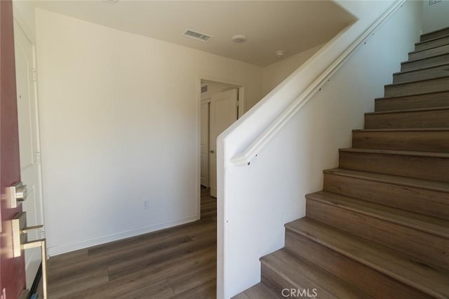 staircase with baseboards, visible vents, and wood finished floors
