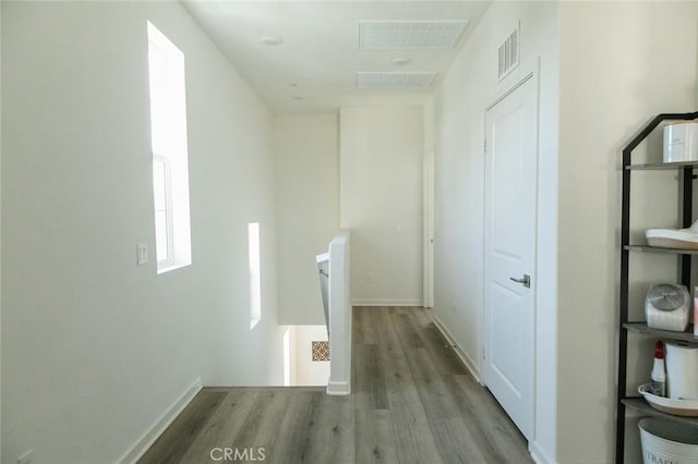 hall featuring an upstairs landing, wood finished floors, and visible vents