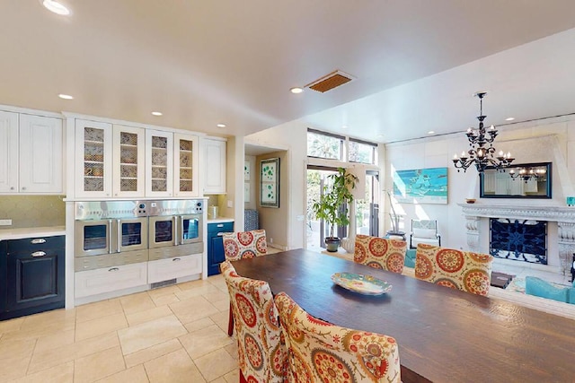 tiled dining area with a chandelier and a fireplace