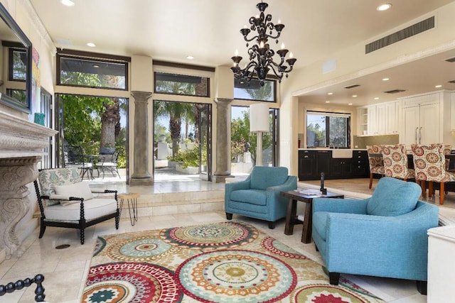 living room with decorative columns, a high ceiling, a notable chandelier, light tile patterned flooring, and sink