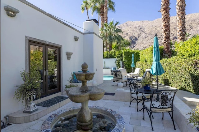 view of patio / terrace featuring french doors and a mountain view