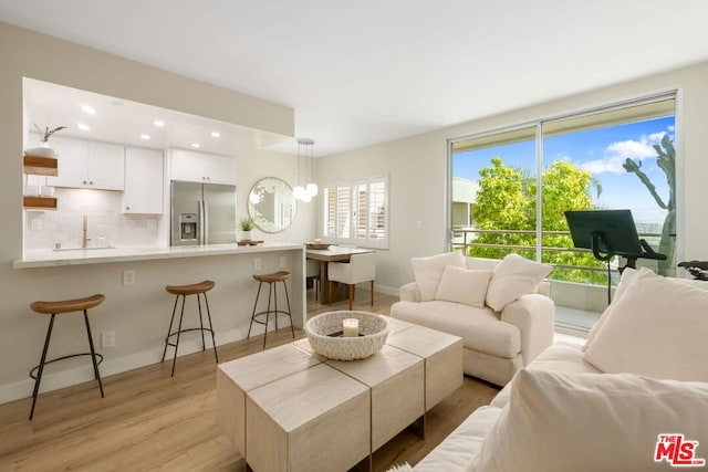 living room with sink, a chandelier, and light hardwood / wood-style flooring