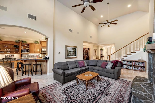 living room featuring ceiling fan, crown molding, and a high ceiling