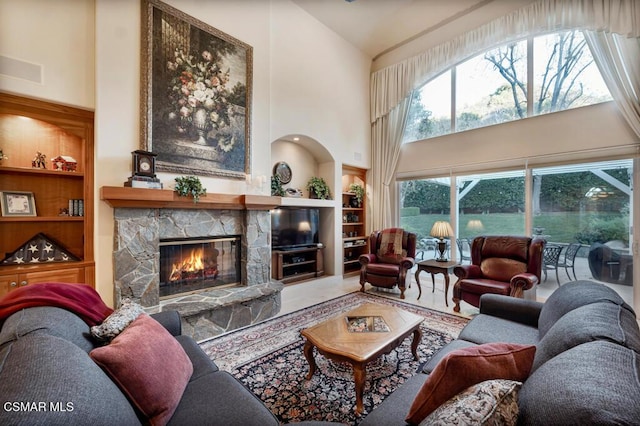 living room featuring built in features, a towering ceiling, and a fireplace