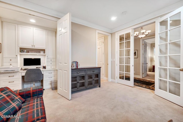 carpeted office space with built in desk, a chandelier, french doors, and ornamental molding