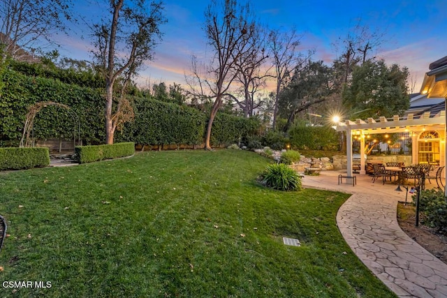 yard at dusk featuring a pergola and a patio area