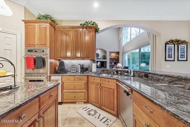 kitchen featuring appliances with stainless steel finishes, tasteful backsplash, dark stone countertops, sink, and ornamental molding