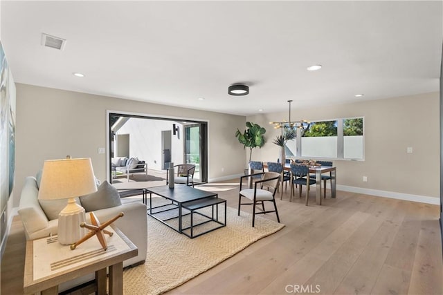 living room featuring a notable chandelier and light hardwood / wood-style floors