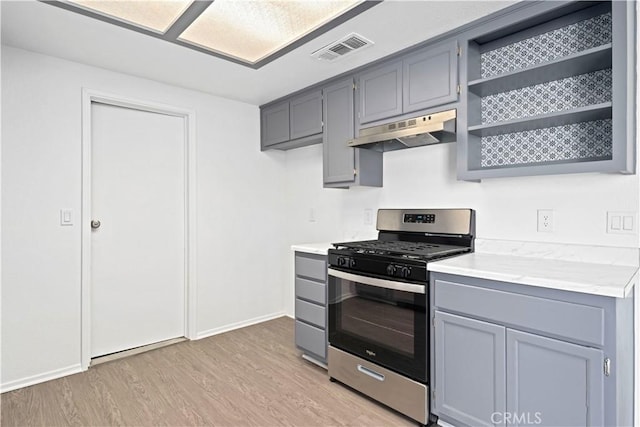 kitchen featuring light wood-type flooring, stainless steel gas range oven, and gray cabinets