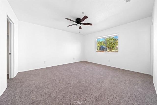 spare room featuring ceiling fan and dark colored carpet