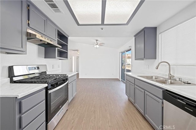 kitchen featuring appliances with stainless steel finishes, light hardwood / wood-style flooring, sink, ceiling fan, and gray cabinetry