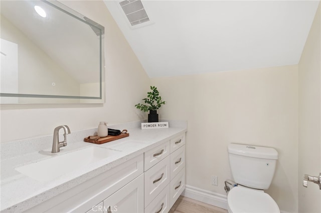 bathroom with lofted ceiling, toilet, and vanity