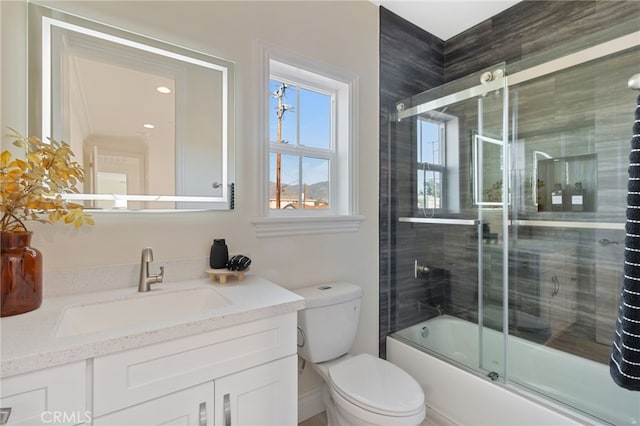 full bathroom with toilet, vanity, and bath / shower combo with glass door