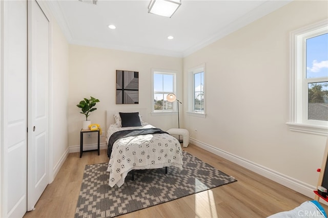 bedroom with light wood-type flooring, a closet, and crown molding