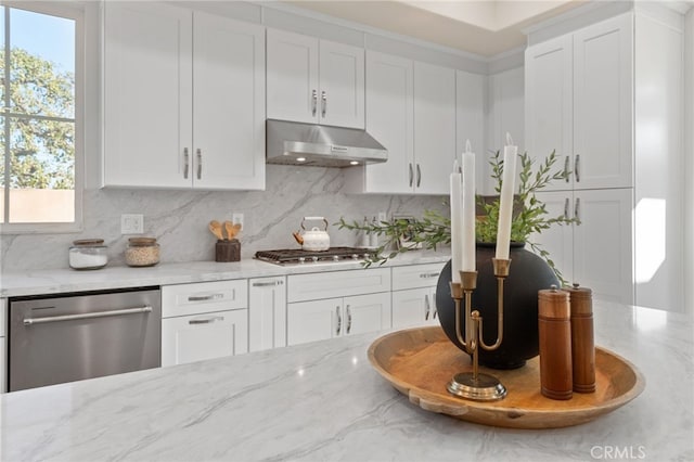 kitchen with appliances with stainless steel finishes, white cabinetry, light stone countertops, and tasteful backsplash